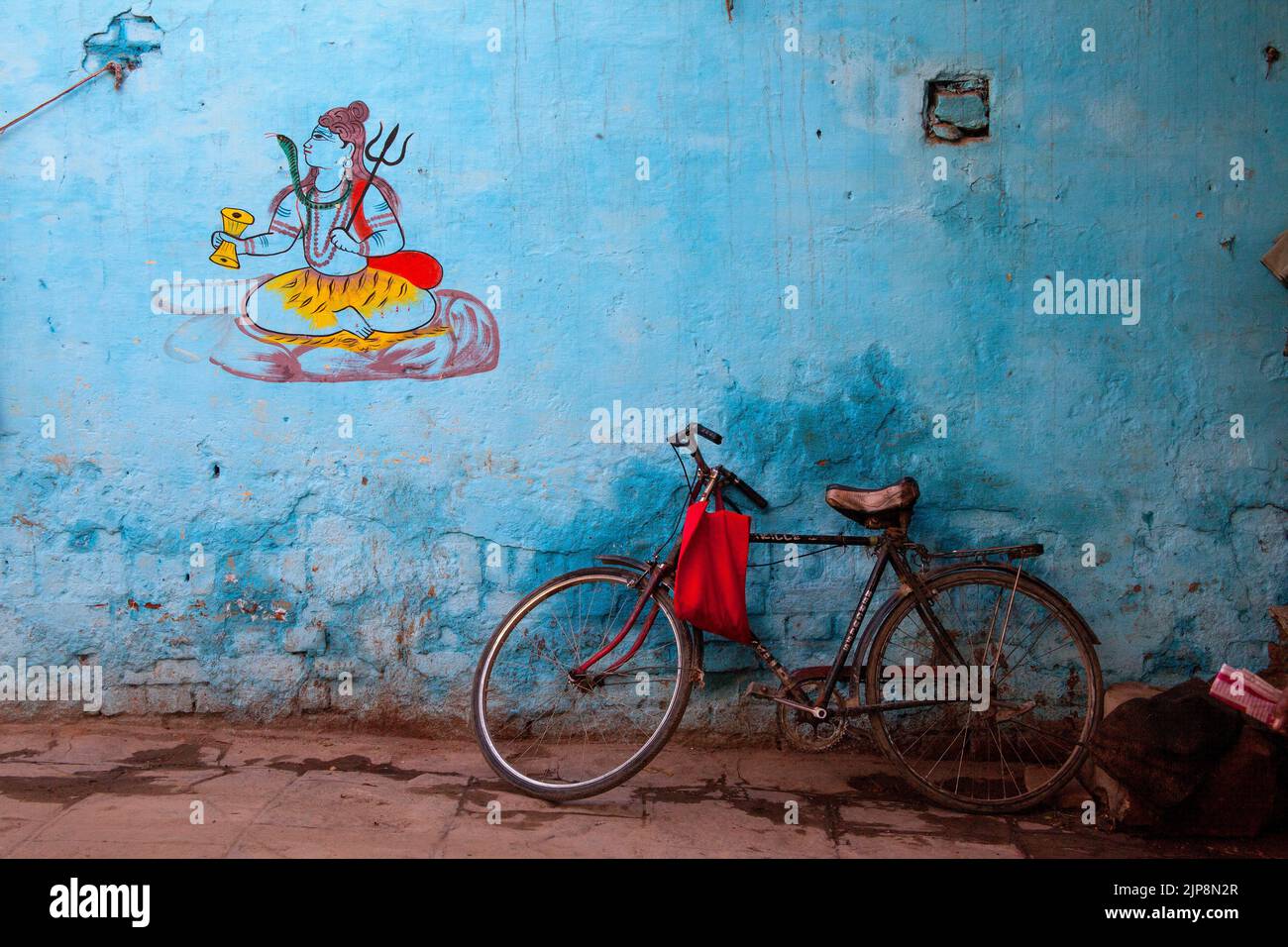 Bicicleta de pie contra la pared con pintura Shiva, Varanasi, Banaras, Benaras, Kashi, Uttar Pradesh, India Foto de stock