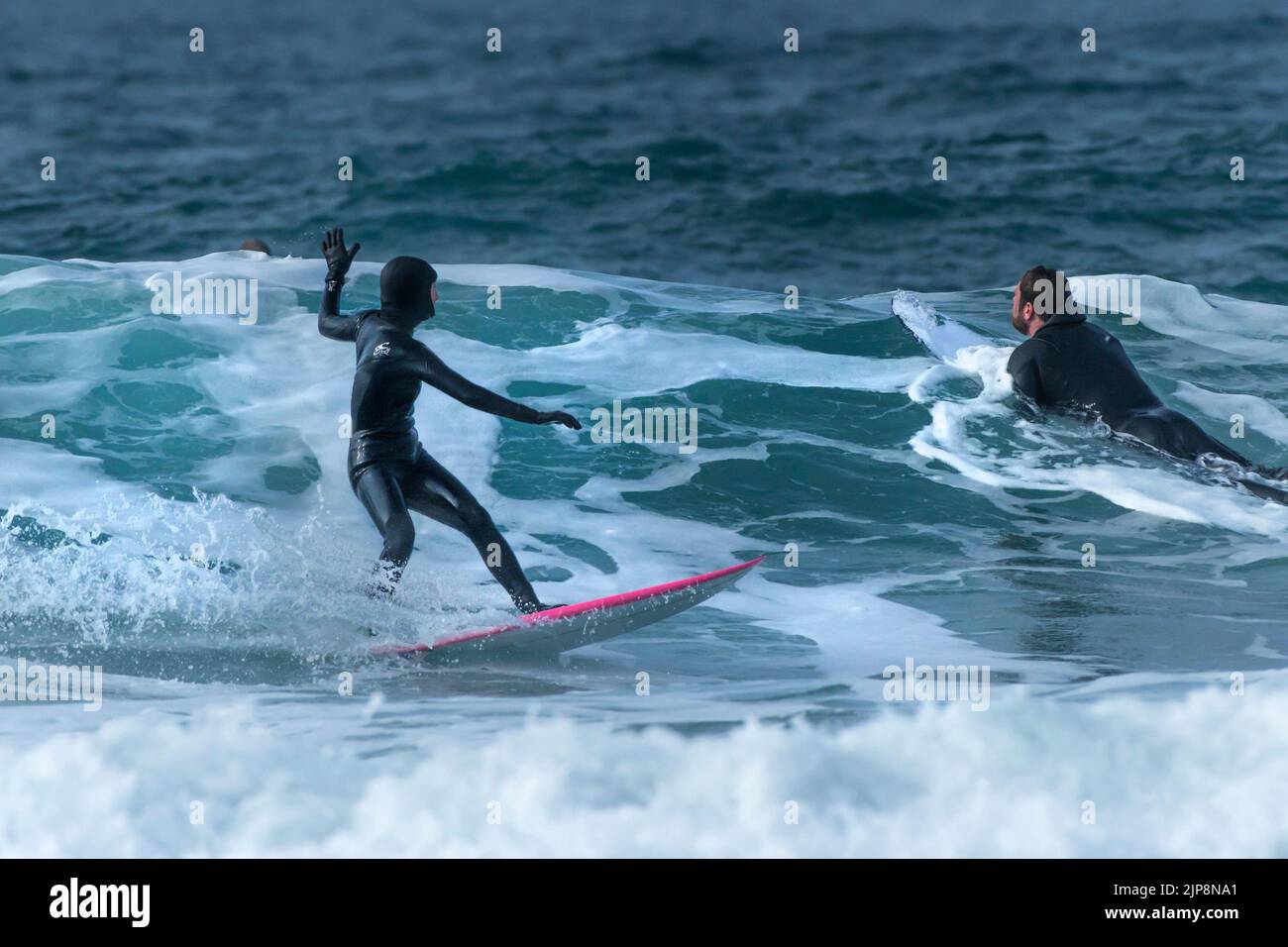 Surfistas disfrutando de la acción de surf en invierno en Fistral en Newquay en Cornwall en el Reino Unido. Foto de stock