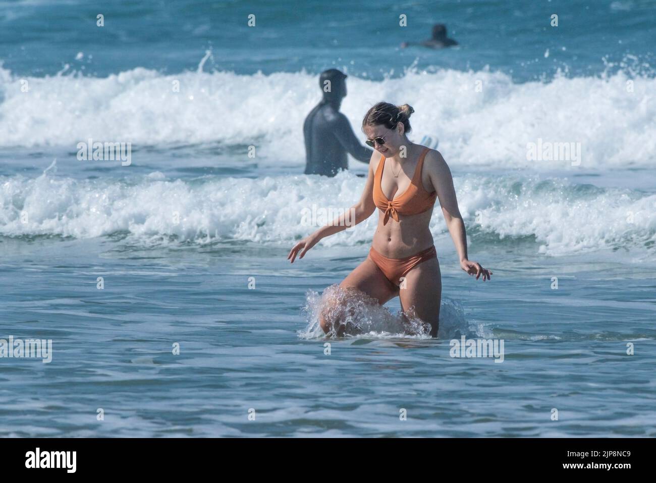 Una atractiva mujer de vacaciones en un bikini saliendo del mar en Fistral en Newquay en Cornwall en el Reino Unido. Foto de stock