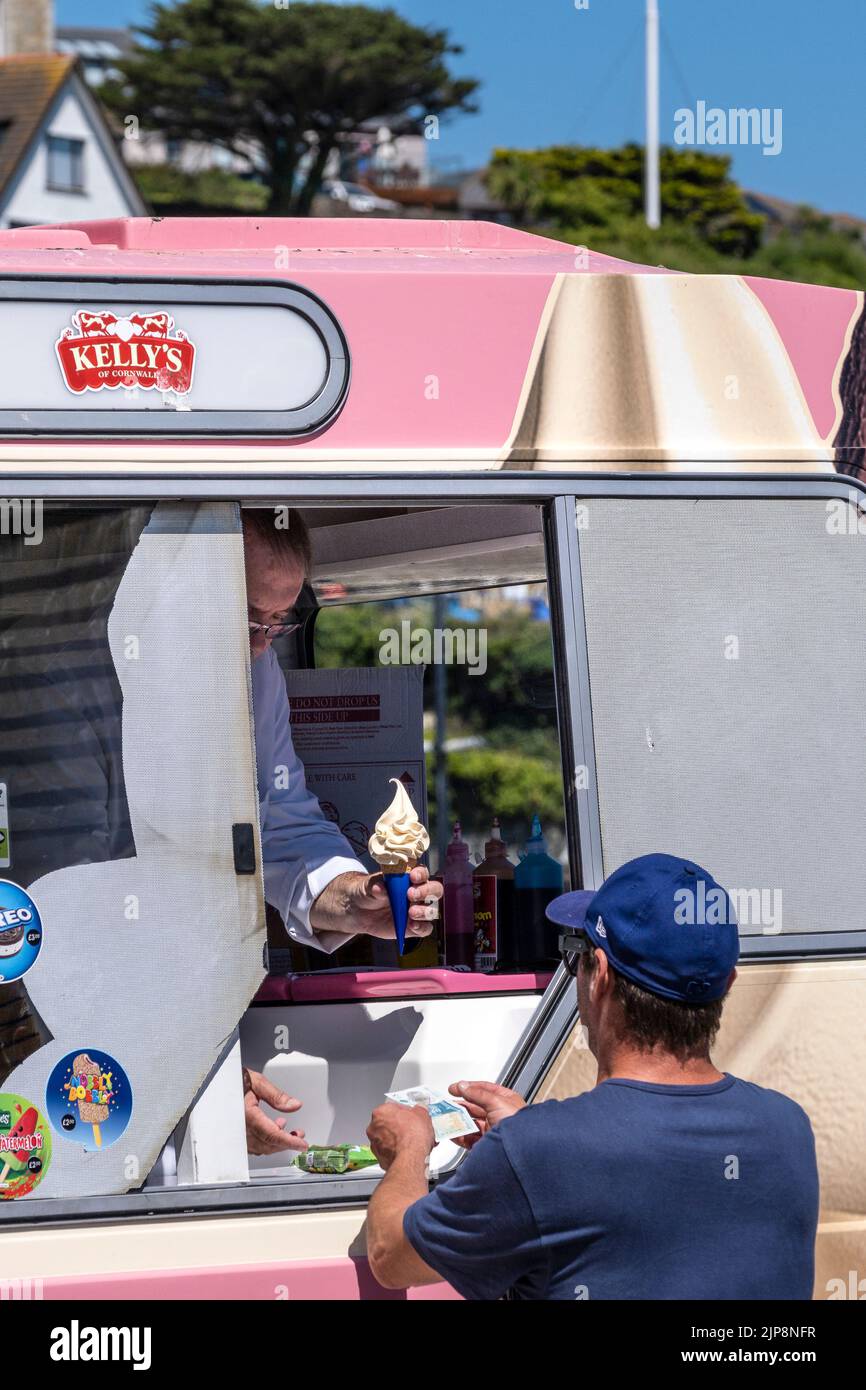 Un turista que paga por comprar un helado de una furgoneta Kelly's Ice Cream en Cornwall. En Cornwall en Inglaterra en el Reino Unido. Foto de stock