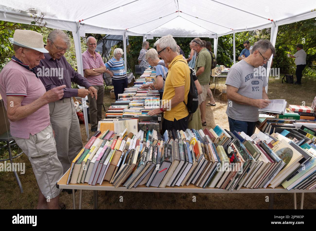 Personas mayores que compran libros de segunda mano en un puesto de libros de segunda mano, la aldea anual fete, Burton Bradstock Village, Dorset Reino Unido Foto de stock