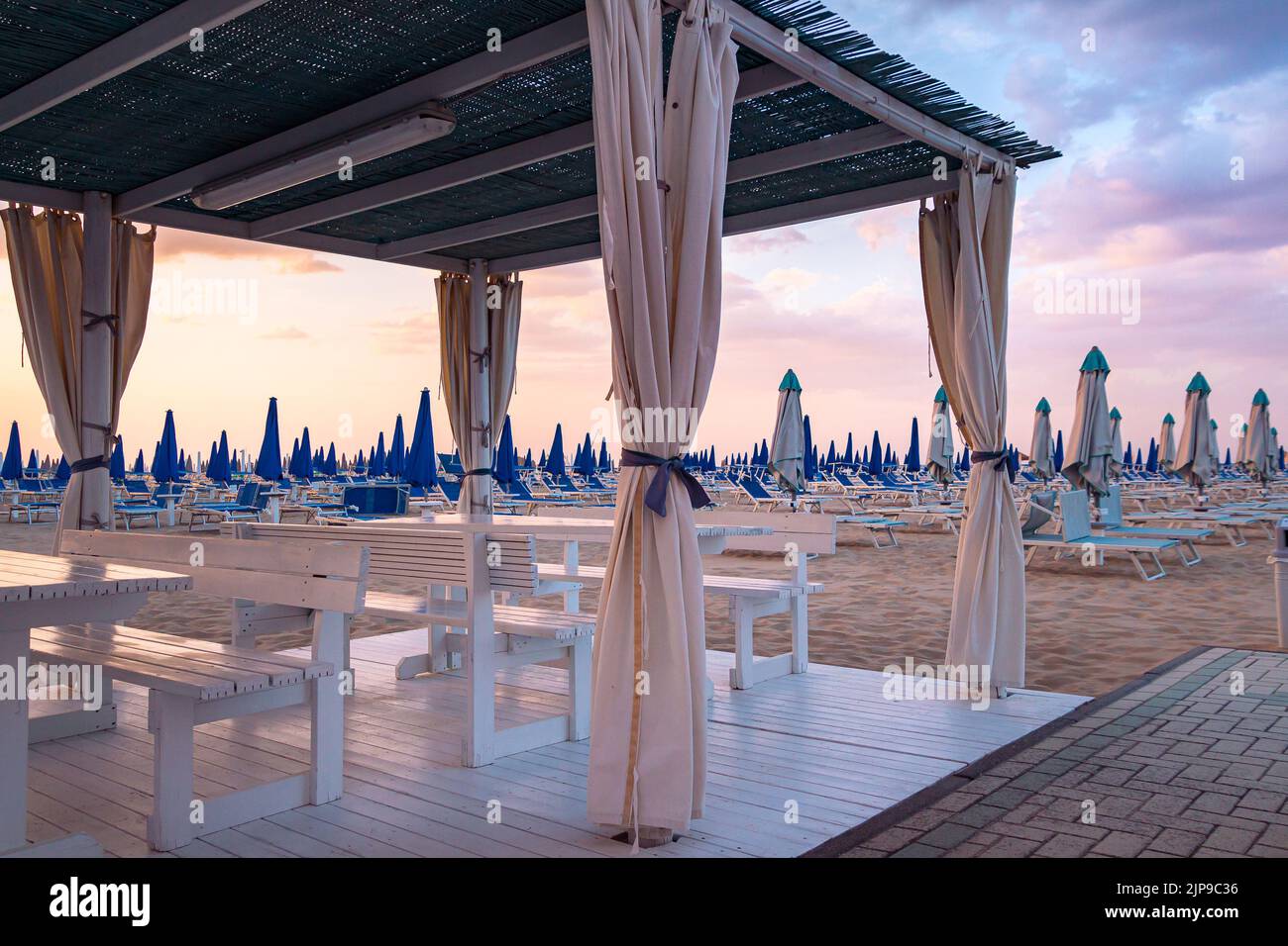 Vista sobre las tumbonas vacías en la playa de arena de Rivazzurra, Rimini, Italia al atardecer Foto de stock