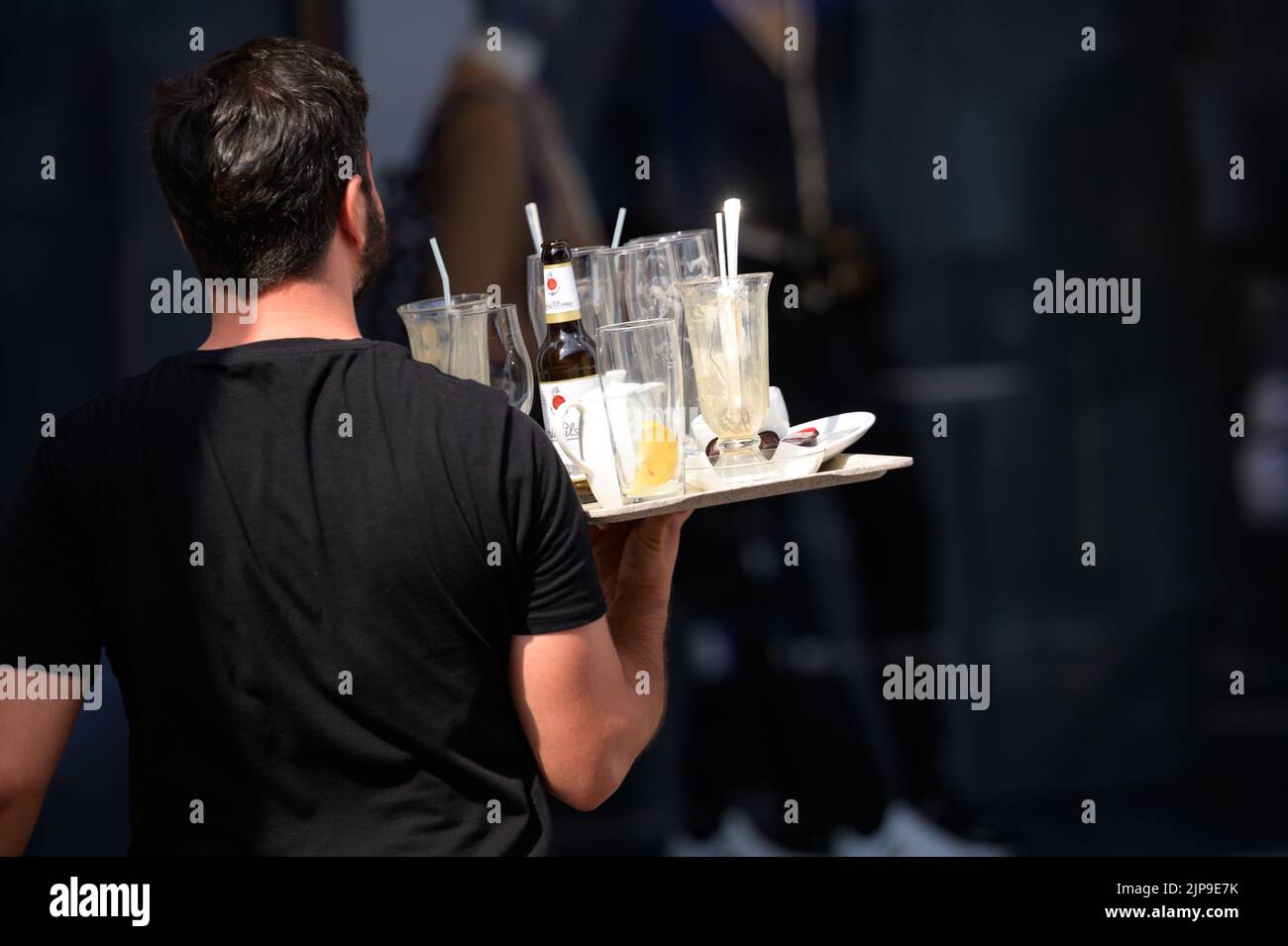 Hamburgo, Alemania. 16th de Ago de 2022. Un camarero del Alsterarkaden lleva una bandeja con vasos usados y botellas vacías. Crédito: Jonas Walzberg/dpa/Alamy Live News Foto de stock