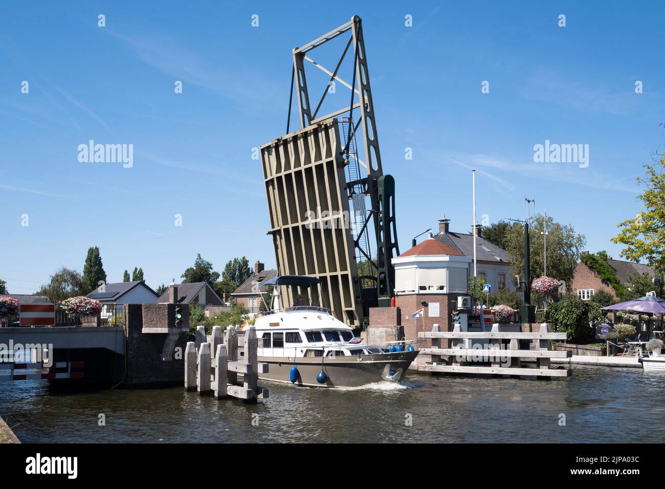 El barco navega por el río 'Oude Rijn' (antiguo Rin) bajo el puente levadizo de acero abierto en el pueblo de Koudekerk aan den Rijn, Países Bajos Foto de stock