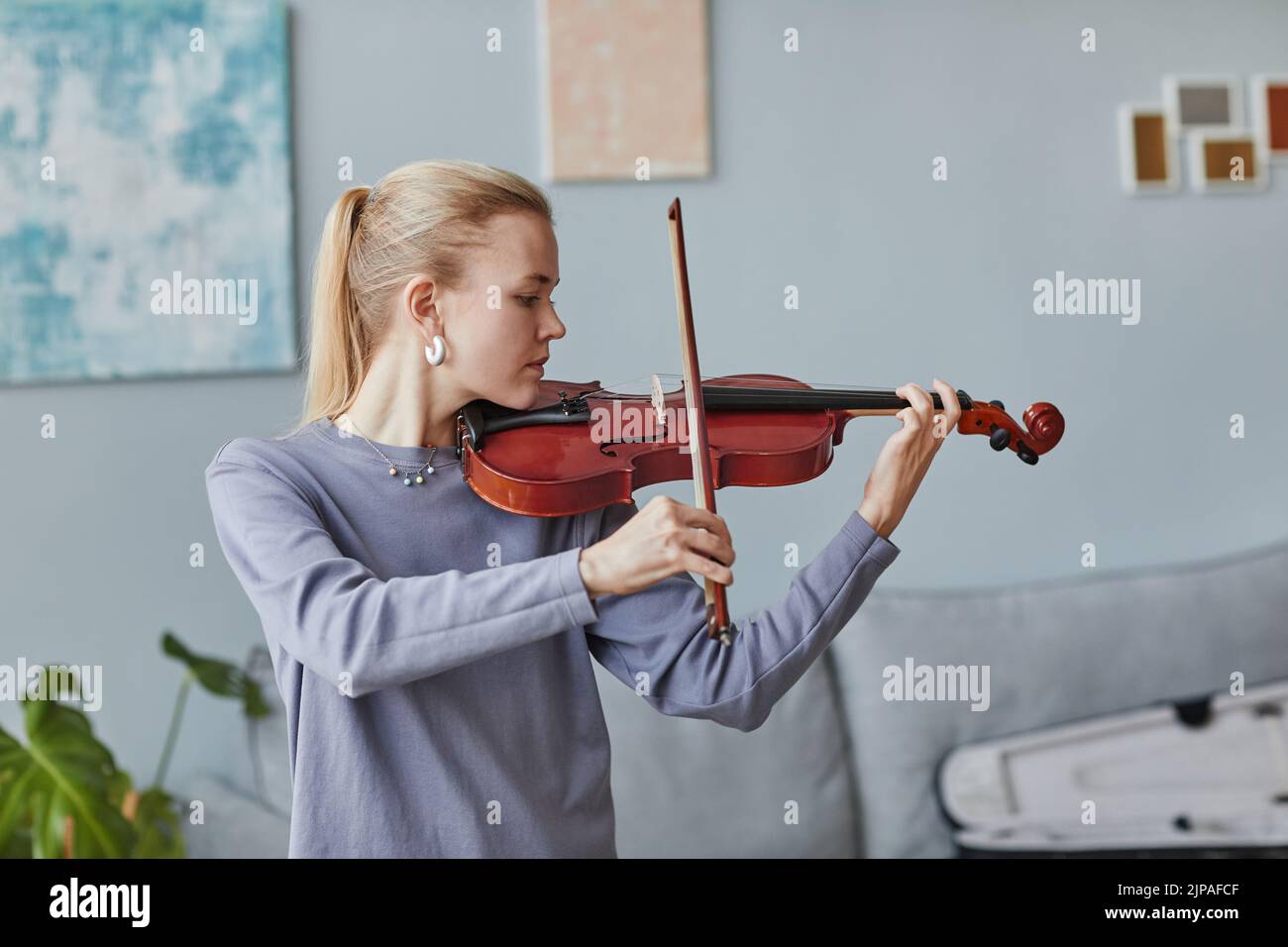 Retrato mínimo en la cintura de una joven tocando violín en casa o en un estudio de música, espacio de copia Foto de stock