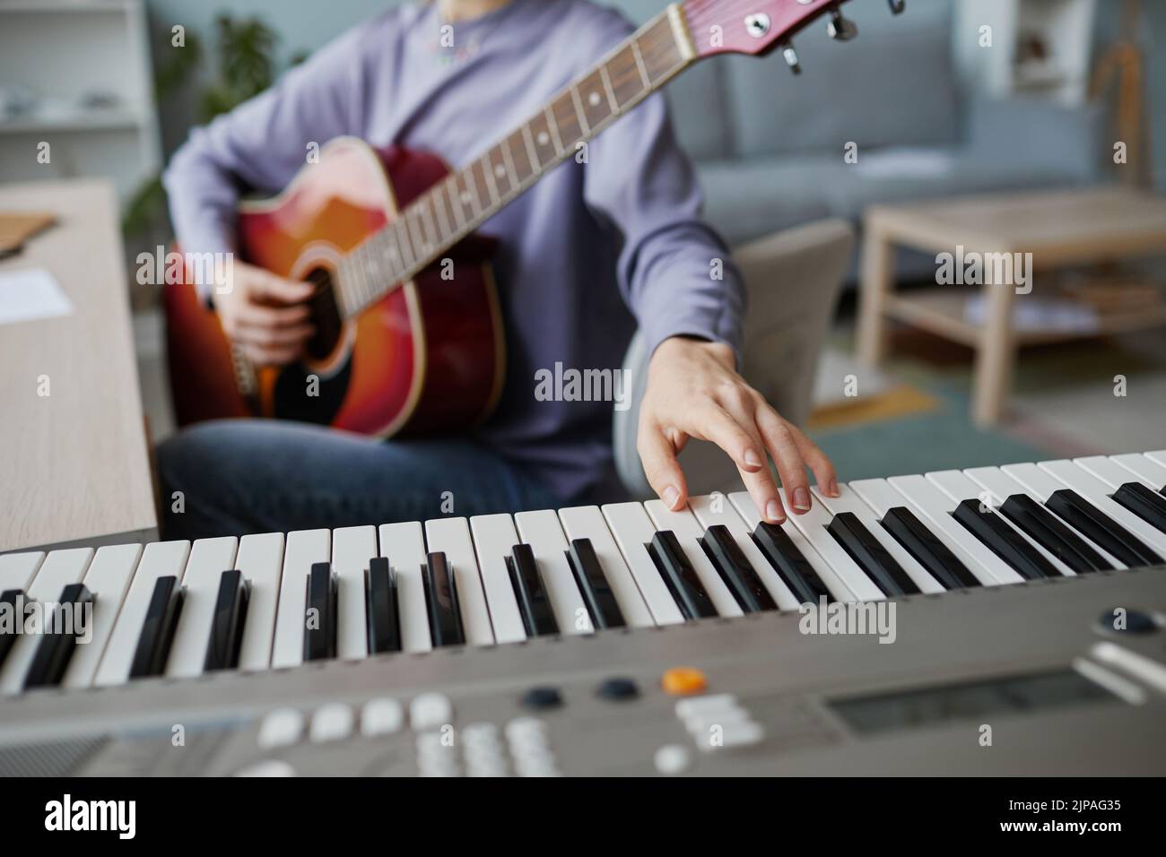 Primer plano de mujer joven pulsando la tecla del piano mientras compone música en casa, espacio de copia Foto de stock