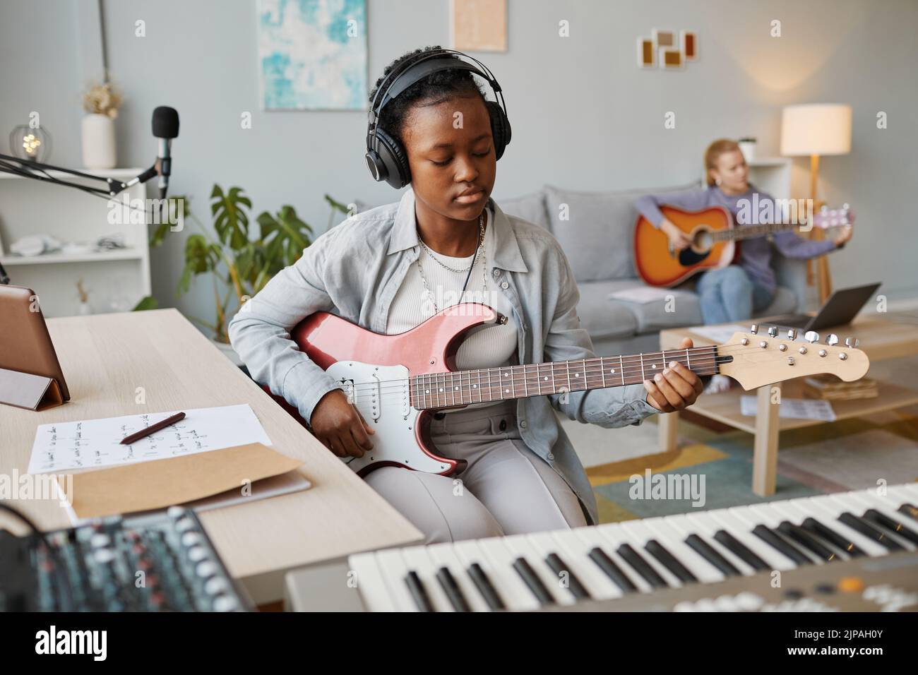 Retrato de una joven mujer negra tocando la guitarra eléctrica en el estudio y componiendo música, espacio de copia Foto de stock