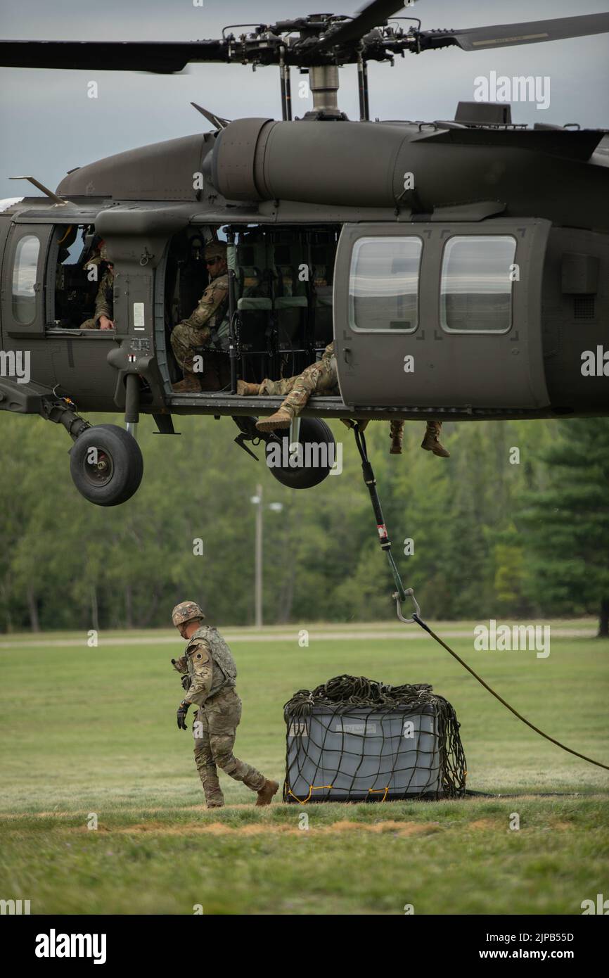 Soldados del Ejército de los Estados Unidos, Batallón de Apoyo de Brigada 237th, Cleveland, Ohio, conectan un cable durante una misión de cabestrillo en el Campo del Desfile de Camp Grayling, Mich., 14 de agosto de 2022 durante el Ejercicio de Huelga Norte 22-2. Northern Strike está diseñado para desafiar a aproximadamente 7.400 miembros del servicio con múltiples formas de capacitación que promueven la interoperabilidad entre socios multicomponentes, multinacionales e interinstitucionales. (EE. UU Foto del Ejército por Sgt. Dustin Stewart). Foto de stock