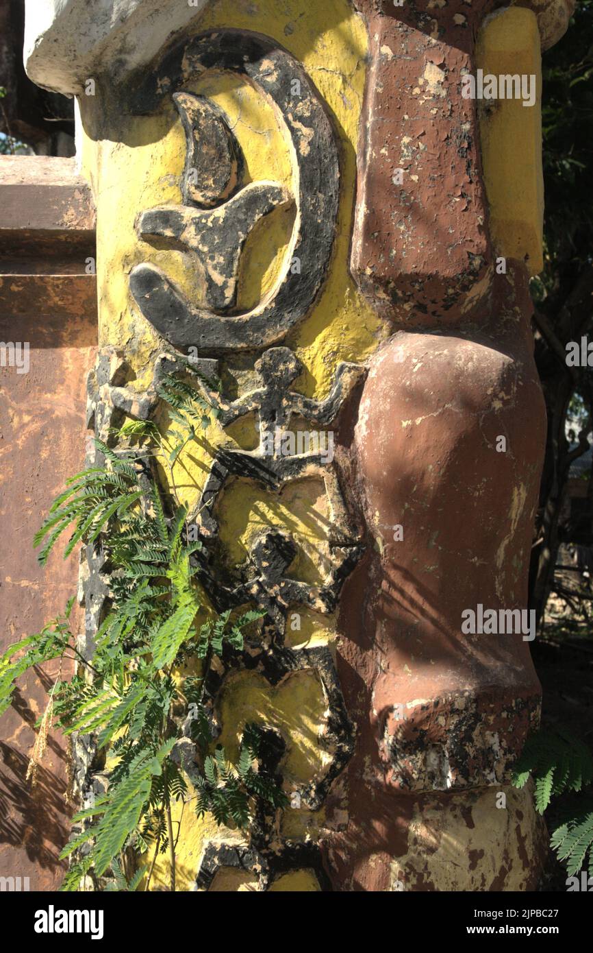 La versión moderna del relieve ornamental de 'manusia kangkang' (figura humana con patas espradadas) se ve en un poste de la puerta delante de un molino abandonado de aceite de sándalo en Kupang, East Nusa Tenggara, Indonesia. Foto de stock