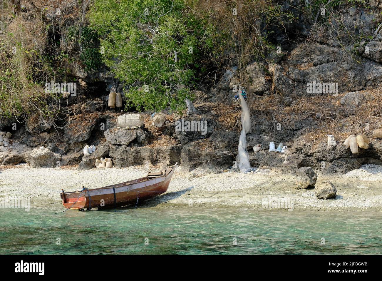 Indonesia Alor Island - Playa con bote de pesca y equipo de pesca Foto de stock