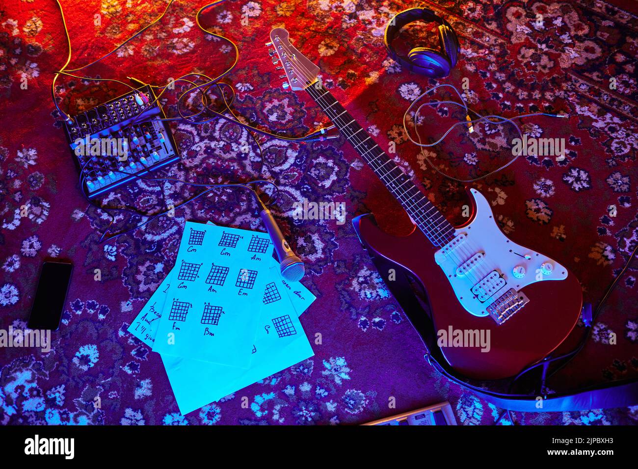 Vista superior de fondo de guitarra eléctrica y notas musicales en alfombra ornamentada en estudio de casa, espacio de copia Foto de stock