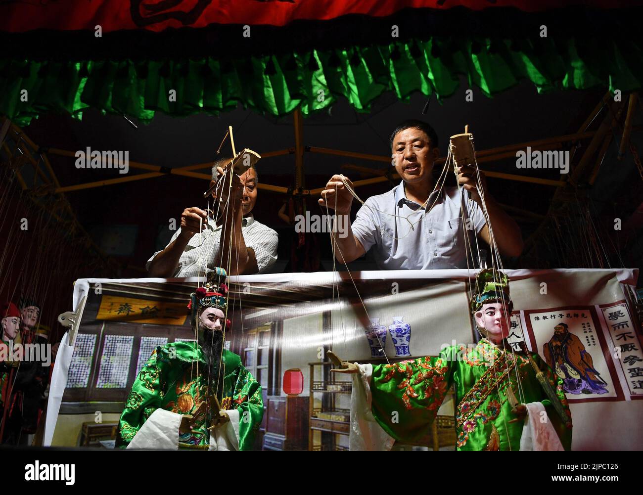(220817) -- NANCHANG, 17 de agosto de 2022 (Xinhua) -- Xie Bangyin (R), cabeza de la compañía títere de Qixin, actúa con miembros de la compañía en el pueblo de Dazhu, en el municipio de Tangfang, en el condado de Guangchang, provincia de Jiangxi, China oriental, el 10 de agosto de 2022. Tangfang es una ópera en la que los artistas interpretan historias con títeres. La marioneta fue catalogada como patrimonio cultural intangible provincial en 2013.En 1997, Xie Bangyin, un tiritero folclórico de Tangfang, fundó la trucha de marionetas de Qixin junto con otros tiriteros. Durante los festivales y eventos importantes, las aldeas locales invitarían a la compañía a realizar títeres. Por encima de las pas Foto de stock