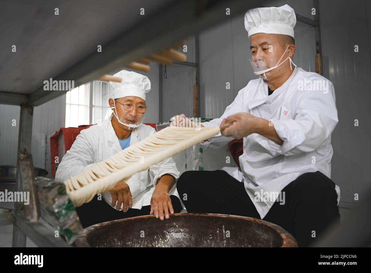 (220817) -- LUONAN, 17 de agosto de 2022 (Xinhua) -- Li Changman (L) enseña a su hijo Li Nianping habilidades para hacer fideos huecos en la aldea de Meidi del municipio de Bao'an en el condado de Luonan de la ciudad de Shangai, provincia de Shaanxi, al noroeste de China, 16 de agosto de 2022. Li Changman, un aldeano de 66 años de edad de Meidi Village, ha aprendido las habilidades únicas para hacer fideos huecos desde que era un adolescente. Él es el heredero de Luonan hecho a mano tallarines de hallow que hacen habilidades que se enumeran como patrimonio cultural intangible provincial. Animó a su hijo a aprender esta habilidad, y también enseñó las habilidades a los aldeanos para que aumentaran Foto de stock