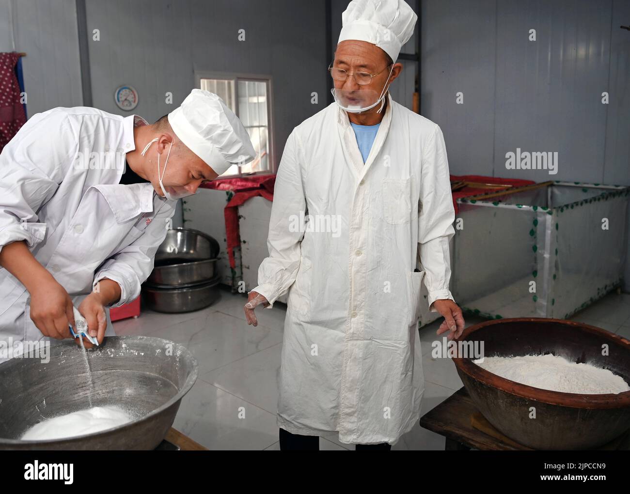(220817) -- LUONAN, 17 de agosto de 2022 (Xinhua) -- Li Changman (R) y su hijo Li Nianping se preparan para hacer fideos huecos en la aldea de Meidi del municipio de Bao'an en el condado de Luonan de la ciudad de Shangai, provincia de Shaanxi, al noroeste de China, 16 de agosto de 2022. Li Changman, un aldeano de 66 años de edad de Meidi Village, ha aprendido las habilidades únicas para hacer fideos huecos desde que era un adolescente. Él es el heredero de Luonan hecho a mano tallarines de hallow que hacen habilidades que se enumeran como patrimonio cultural intangible provincial. Él animó a su niño a aprender esta habilidad, y también enseñó las habilidades a los aldeanos para aumentar thei Foto de stock