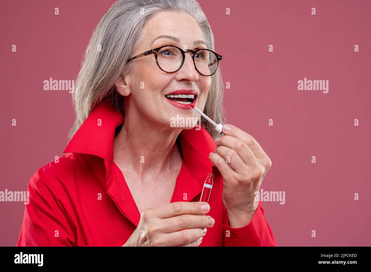 Mujer de mediana edad con buena apariencia poniendo brillo de labios en sus labios Foto de stock