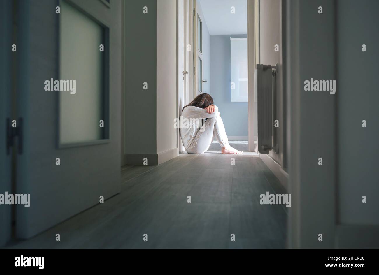 Mujer en pijama sentada en el piso de un centro de salud mental Foto de stock