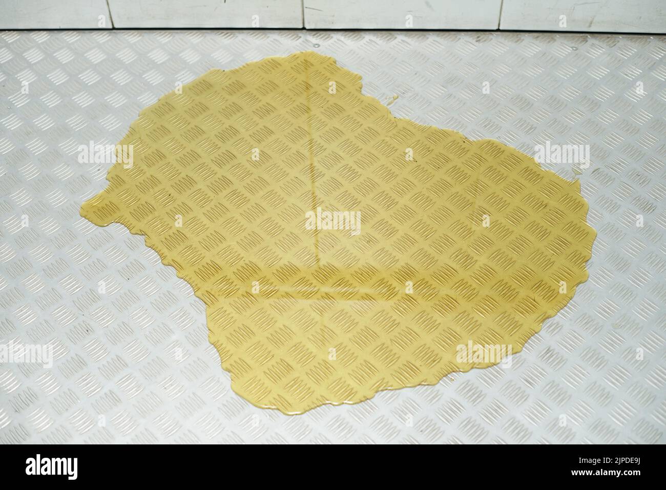 Charco amarillo grande de líquido u orina en el suelo del ascensor. Foto de stock