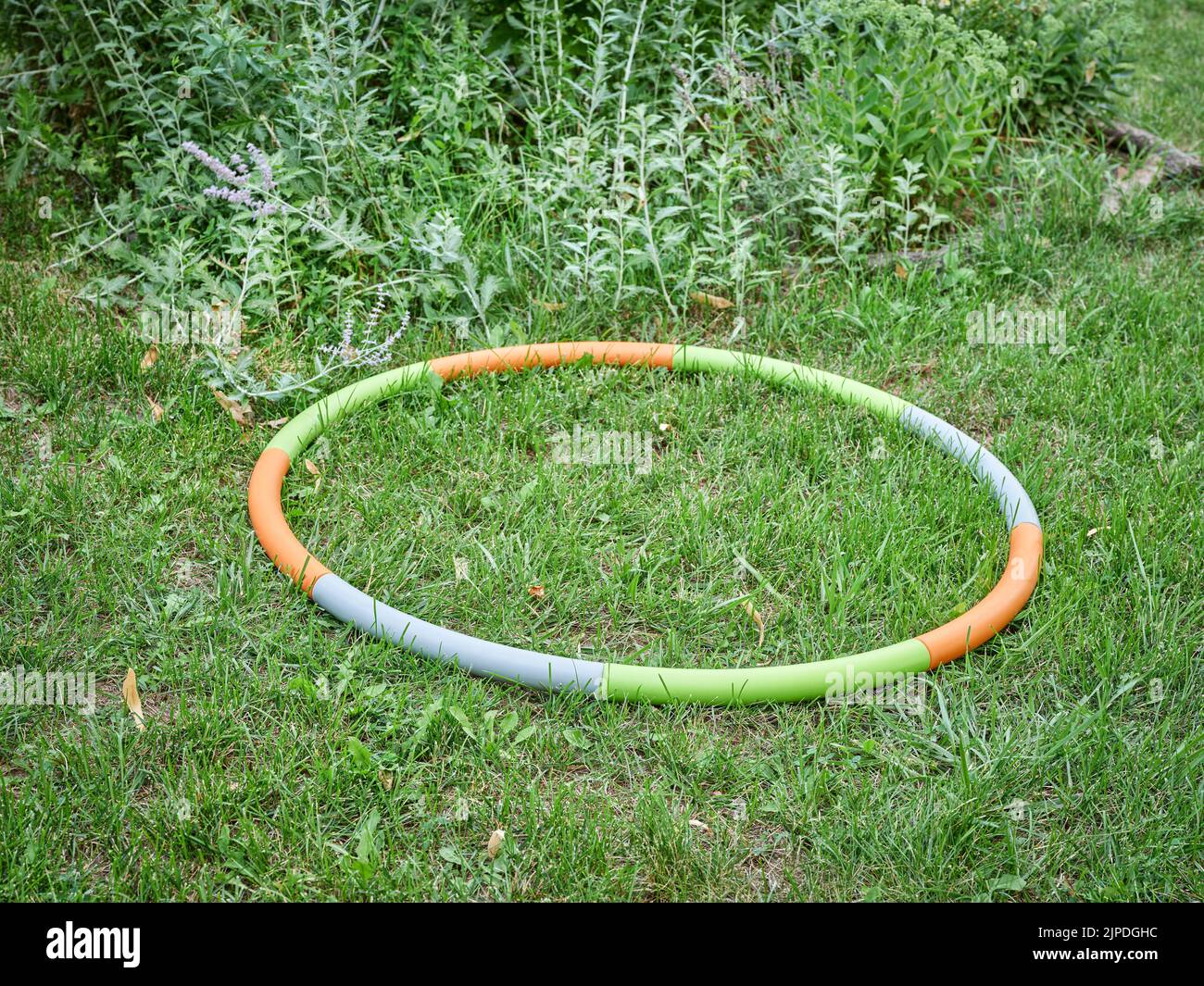 aro de hula ponderado en un jardín de patio trasero en paisaje de verano, concepto de entrenamiento básico Foto de stock