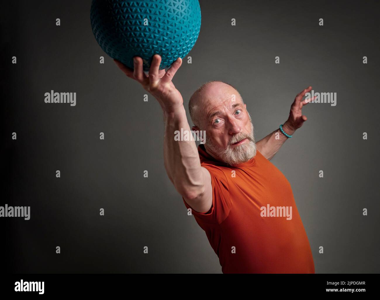 el hombre mayor (a finales de 60s) está haciendo ejercicio con una bola pesada de la slam o de la medicina, la actividad y la aptitud sobre 60 concepto Foto de stock