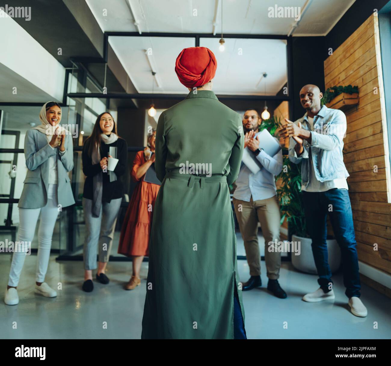 Una mujer de negocios exitosa que recibió un aplauso de sus colegas en una oficina moderna. Mujer de negocios musulmana dando un discurso durante una sta Foto de stock