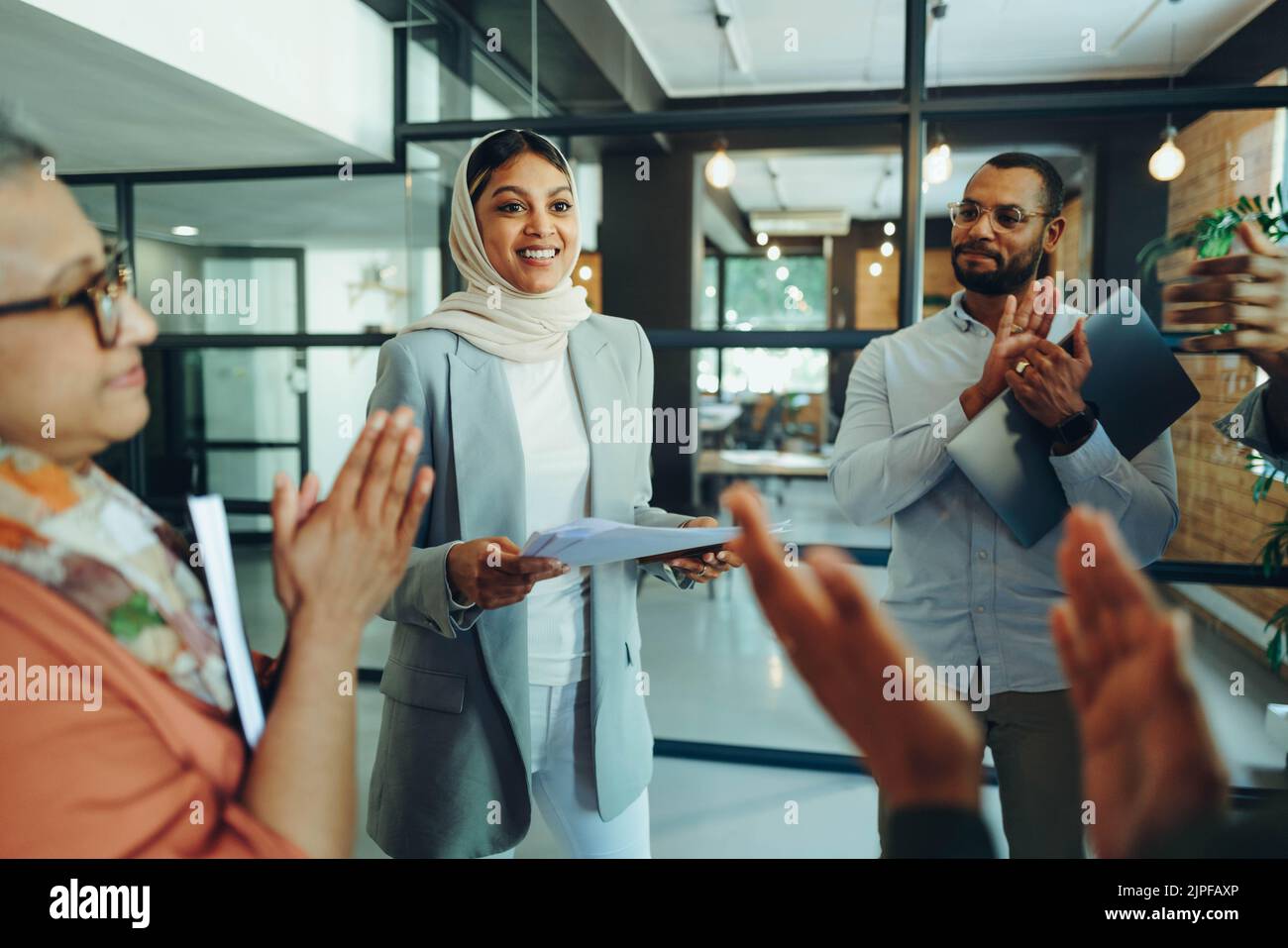 Empresarios multiculturales aplaudieron a su colega durante una reunión en una oficina moderna. Grupo de empresarios exitosos que trabajan como un equipo en un Foto de stock