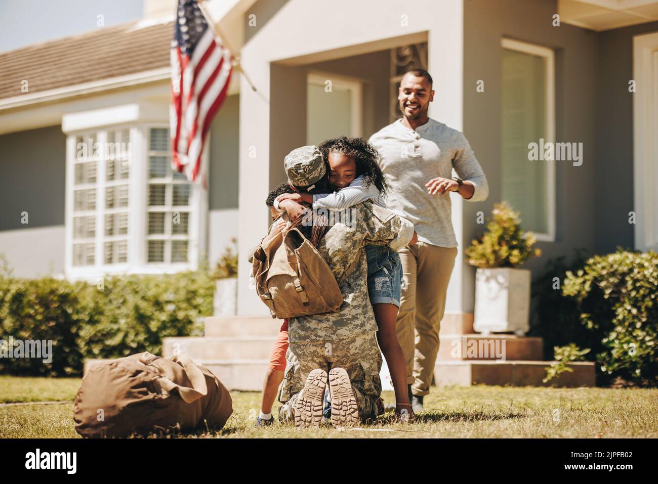 Mujer de servicio estadounidense abrazando a sus hijos después de llegar a casa del ejército. Mujer soldado recibiendo una cálida bienvenida de su marido y sus hijos. Mil Foto de stock