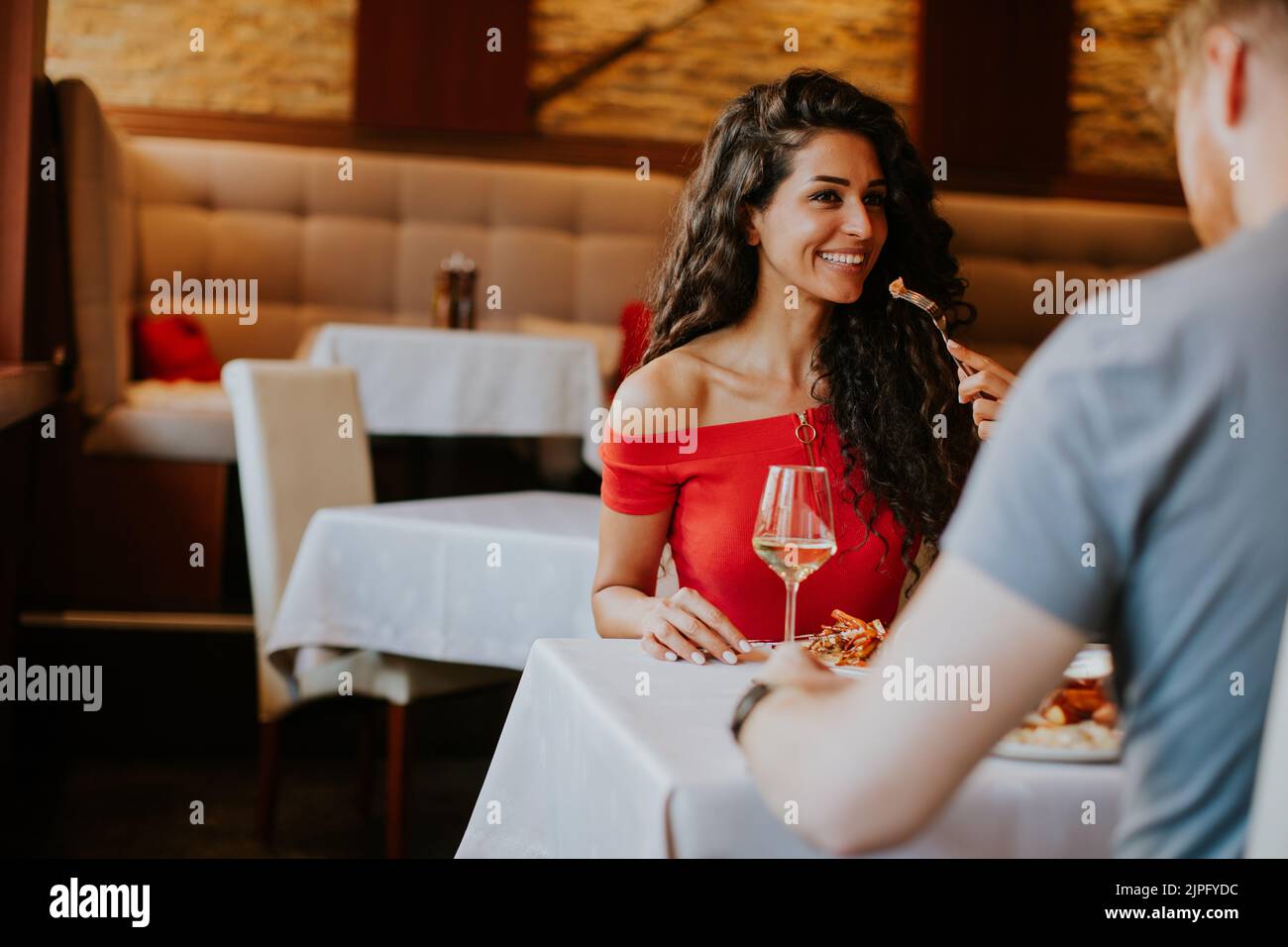 Una hermosa pareja joven almorzando con vino blanco en el restaurante Foto de stock