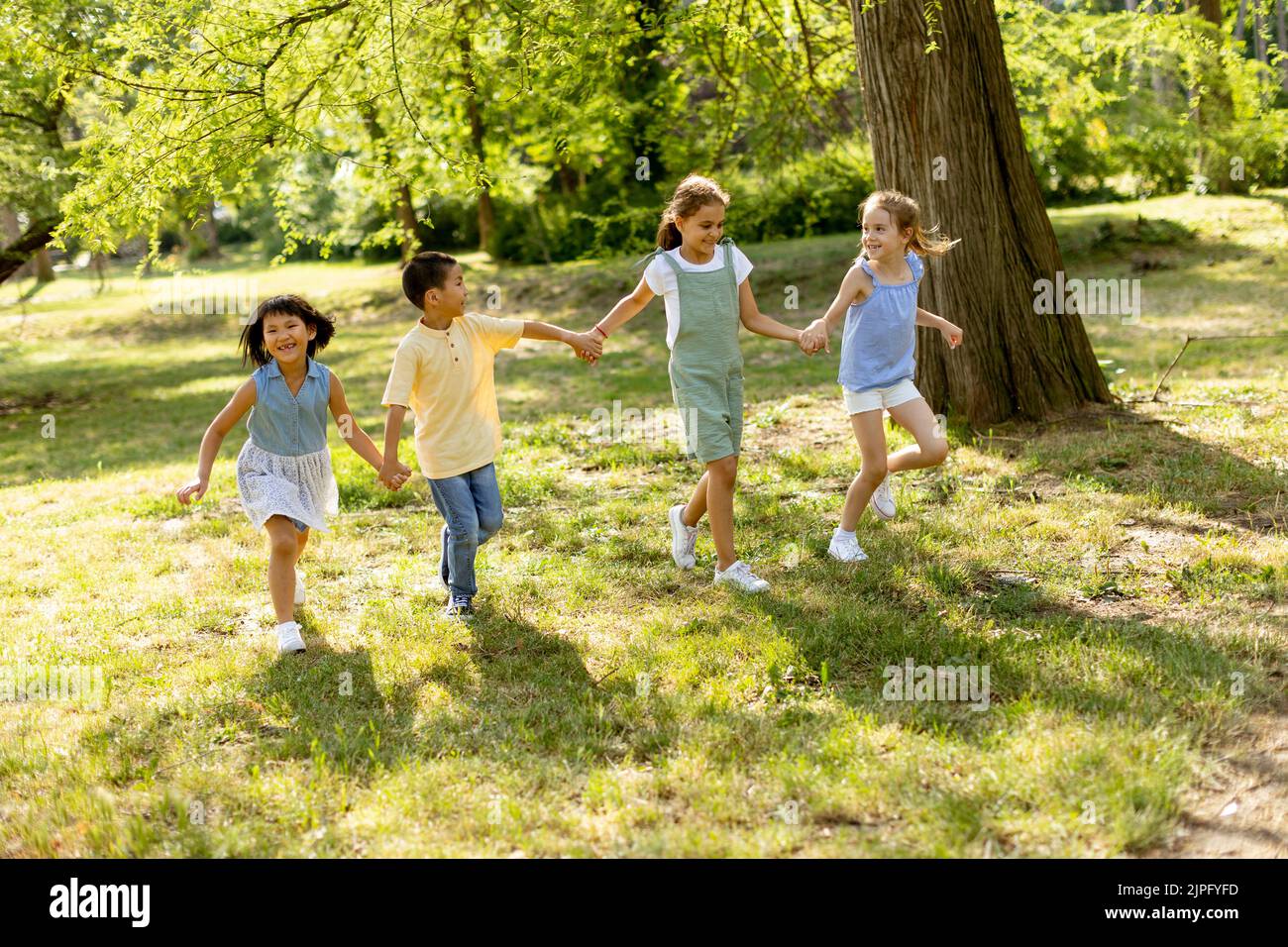 Grupo de lindos niños asiáticos y caucásicos divirtiéndose en el parque Foto de stock