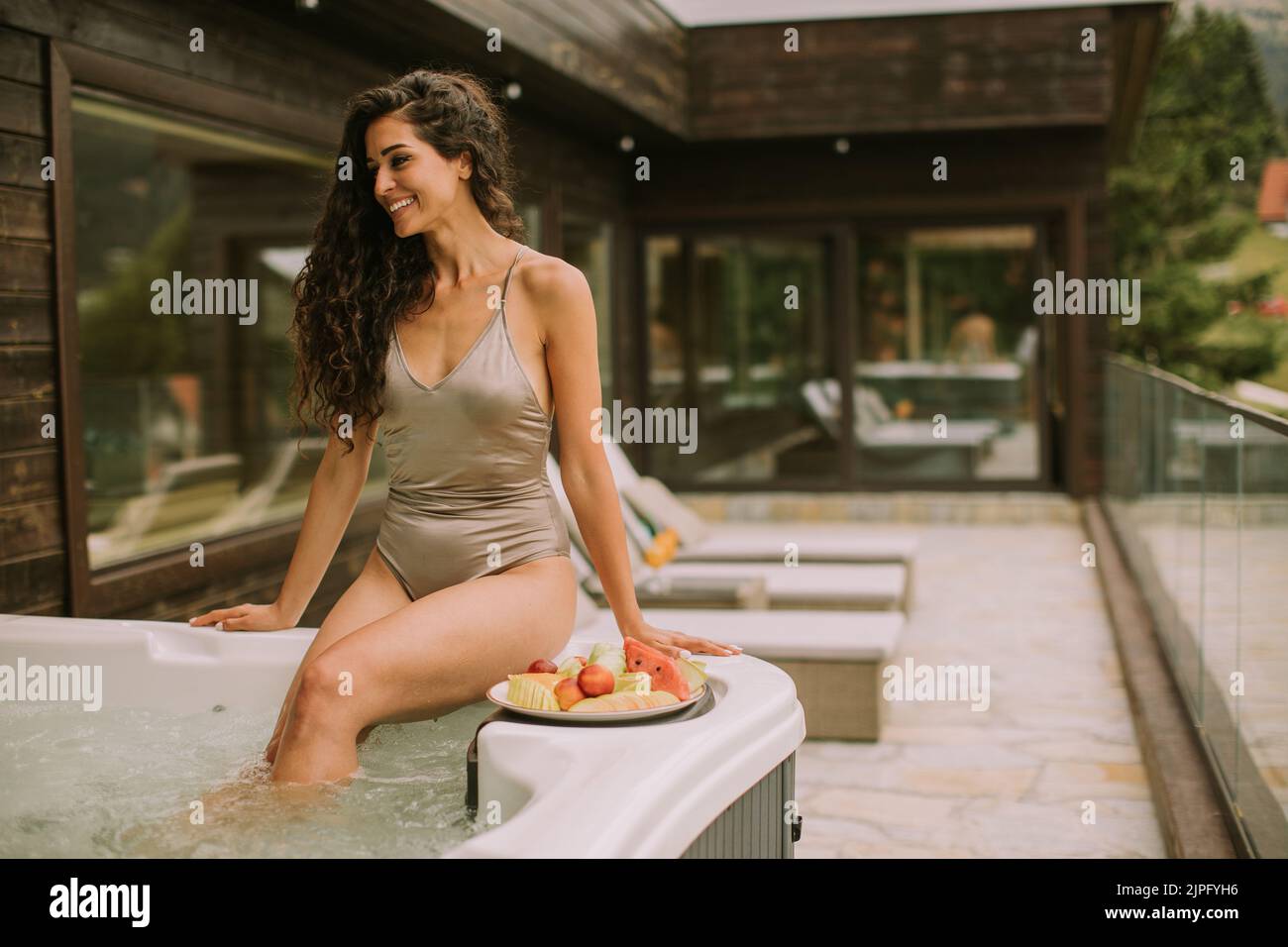 Atractiva mujer joven disfrutando en la bañera de hidromasaje al aire libre en vacaciones Foto de stock