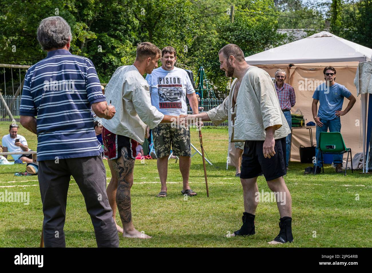 Los competidores se dan la mano al comienzo de la primera ronda del Abierto de Mens en el Grand Cornish Wrestling Tournament en el pintoresco pueblo verde Foto de stock