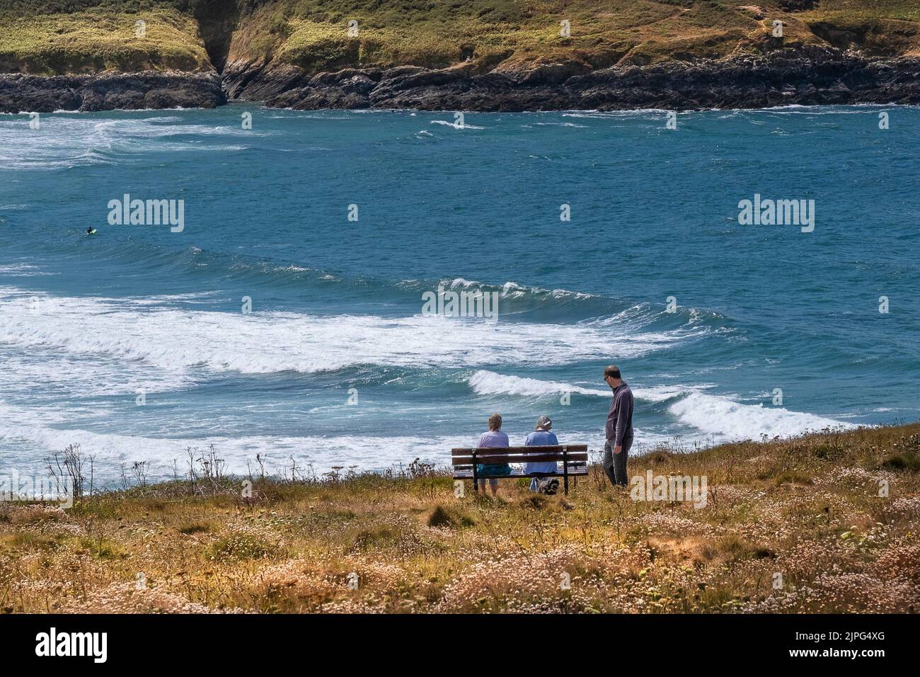 La gente se relaja y disfruta de la vista desde Pentire Point East en la costa de Newquay en Cornwall en el Reino Unido. Foto de stock