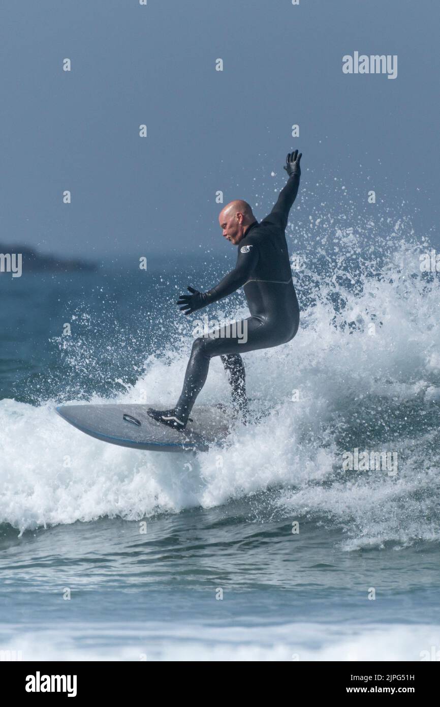 Un surfista masculino que monta una ola en Fistral en Newquay en Cornwall en el Reino Unido. Foto de stock