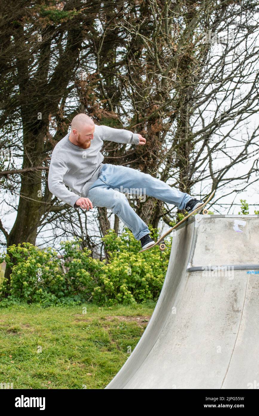 Un hombre maduro skateboarder montando su skateboard en Newquay Concrete Waves Skatepark en Newquay en Cornwall en el Reino Unido. Foto de stock
