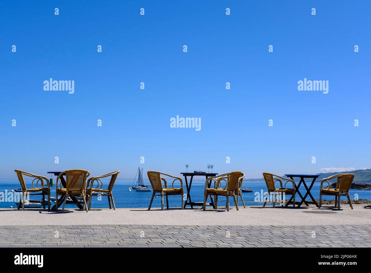 Frankreich, Omonville-la-Rogue, Le Hable, 08.07.2022: Verlassene Tische in der Sonne direkt am Hafen Le Hable vor einem Restaurante en Omonville-la-Rog Foto de stock