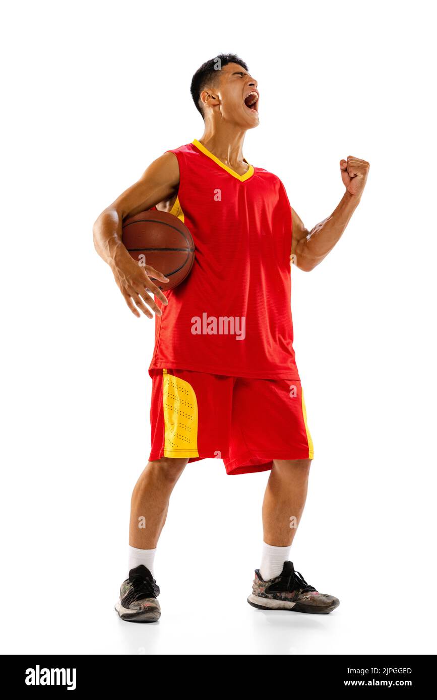 Retrato de joven, jugador de baloncesto aislado sobre fondo blanco de estudio. Emociones. Campeonato ganador Foto de stock