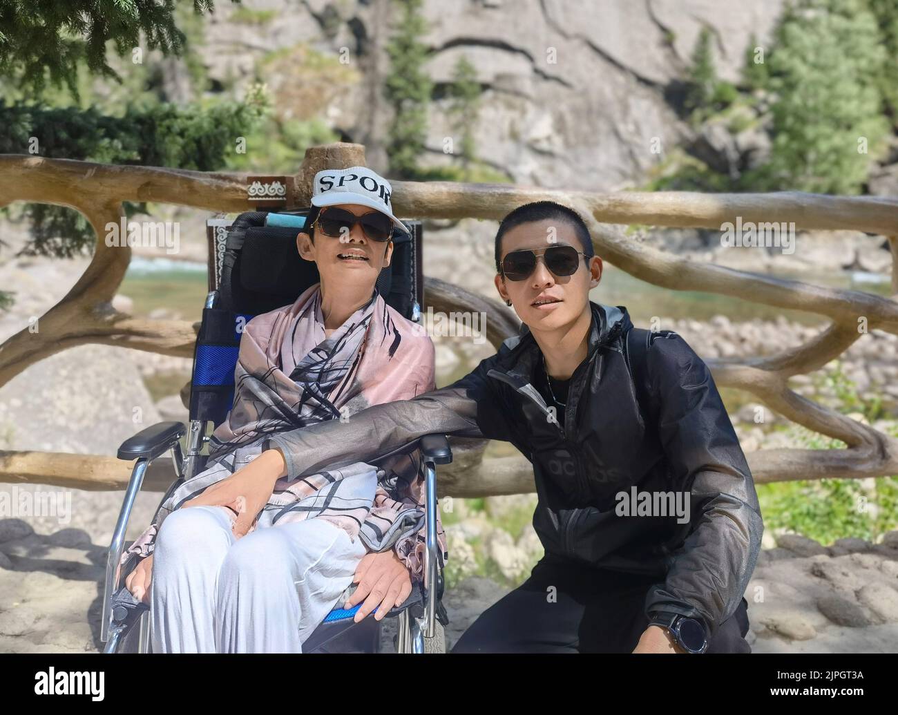 (220818) -- ZHENGZHOU, 18 de agosto de 2022 (Xinhua) -- Zhao Tianci (R) posó para una foto con su madre Liu Wenian durante su viaje a la región autónoma de Xinjiang Uygur, al noroeste de China, el 3 de julio de 2022. Liu Wenyan se considera afortunada. A pesar de estar confinada a una silla de ruedas la mayor parte del tiempo, ha terminado recientemente un viaje por carretera que abarca más de 15.000 km. El viaje de ida y vuelta desde su ciudad natal de Shangqiu, en la provincia de Henan, en el centro de China, a la región autónoma de Xinjiang Uygur, en el noroeste de China, y de nuevo tomó 31 días. Liu, de 52 años, sufre de una enfermedad neurodegenerativa llamada lat. amiotróficos Foto de stock