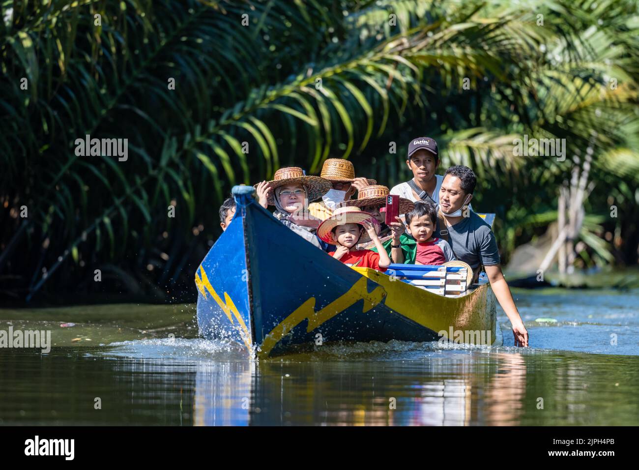 Una familia de turistas felices disfrutan de un paseo en barco por el río. Makassar, Sulawesi, Indonesia. Foto de stock