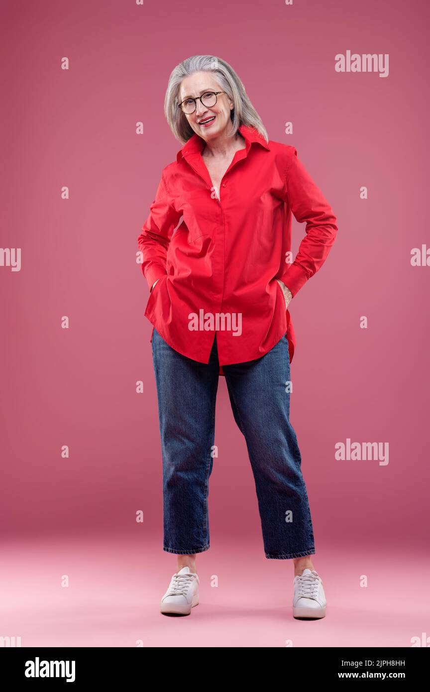 Mujer madura con camisa roja que parece satisfecha Foto de stock