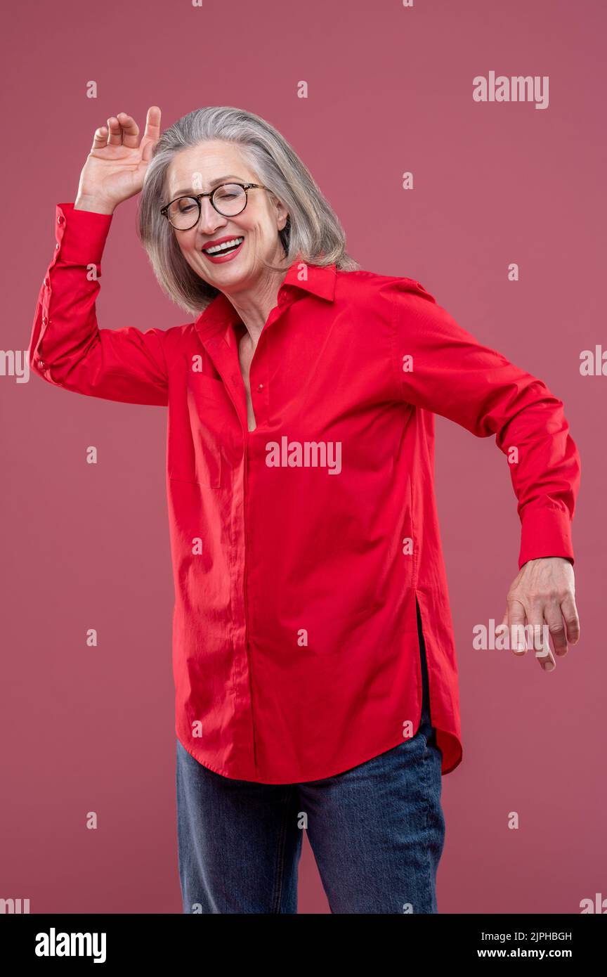 Mujer con camisa roja moviéndose y sonriendo Foto de stock