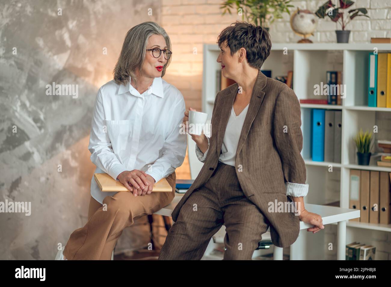 Dos mujeres hablando en el office y mirando involucrados Foto de stock