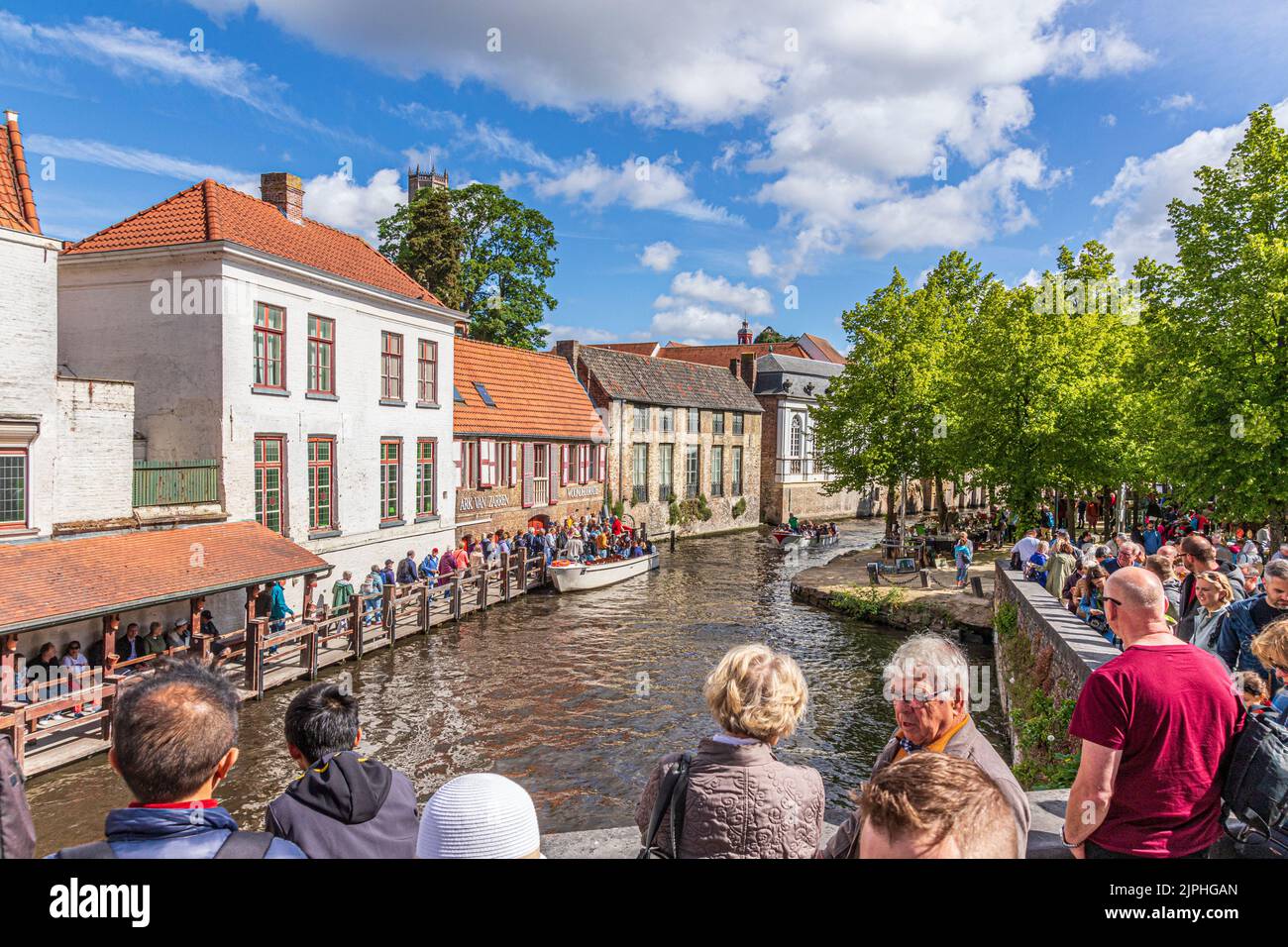 Turistas haciendo cola para una excursión guiada en barco por los canales de Brujas, Bélgica Foto de stock