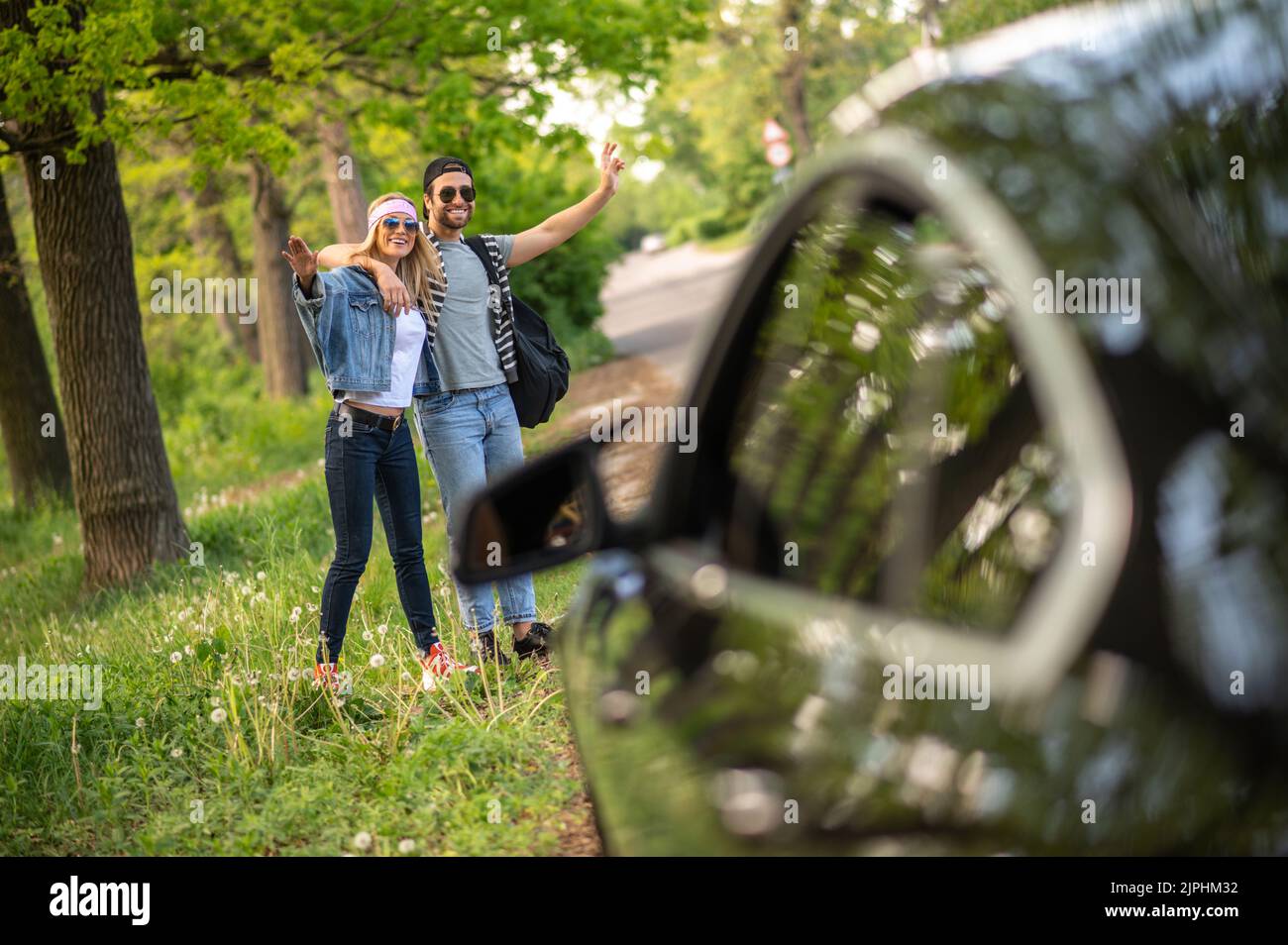 Dos personas tratando de detener el coche en el bosque y luciendo alegre Foto de stock