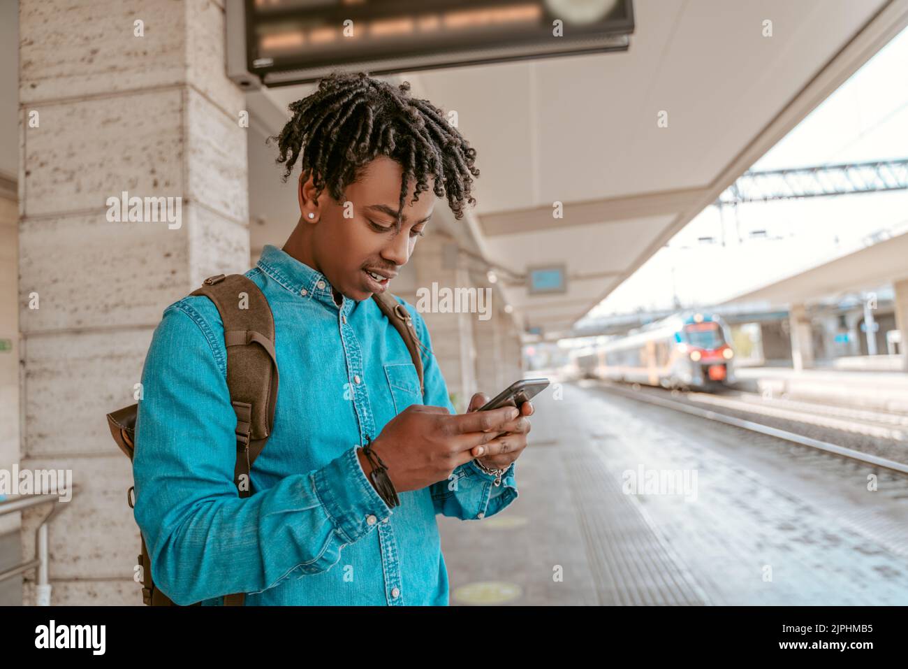 Hombre parado en la plataforma de ferrocarril mirando el smartphone Foto de stock