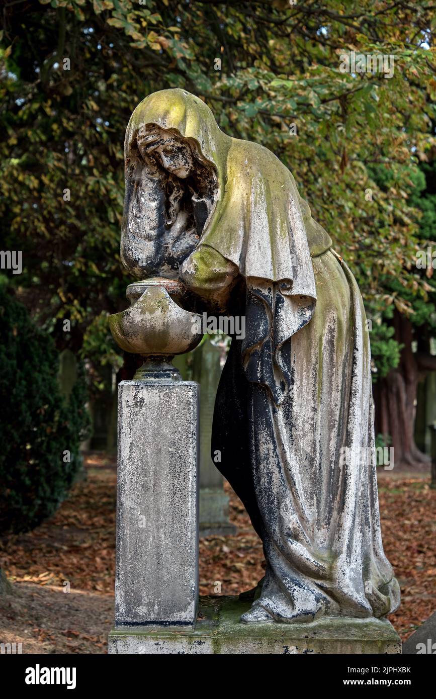 Estatua de una mujer de luto contra un fondo de árboles en el Cementerio Dean, Edimburgo, Escocia, Reino Unido. Foto de stock