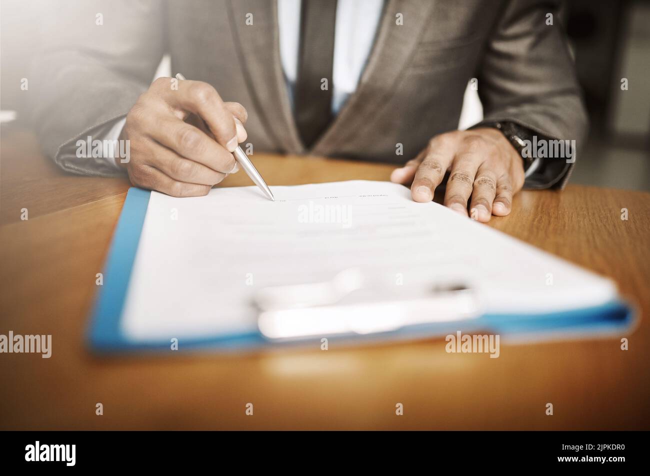 Hacer cambios en la empresa. Un empresario irreconocible firmando documentos dentro de la oficina durante el día. Foto de stock