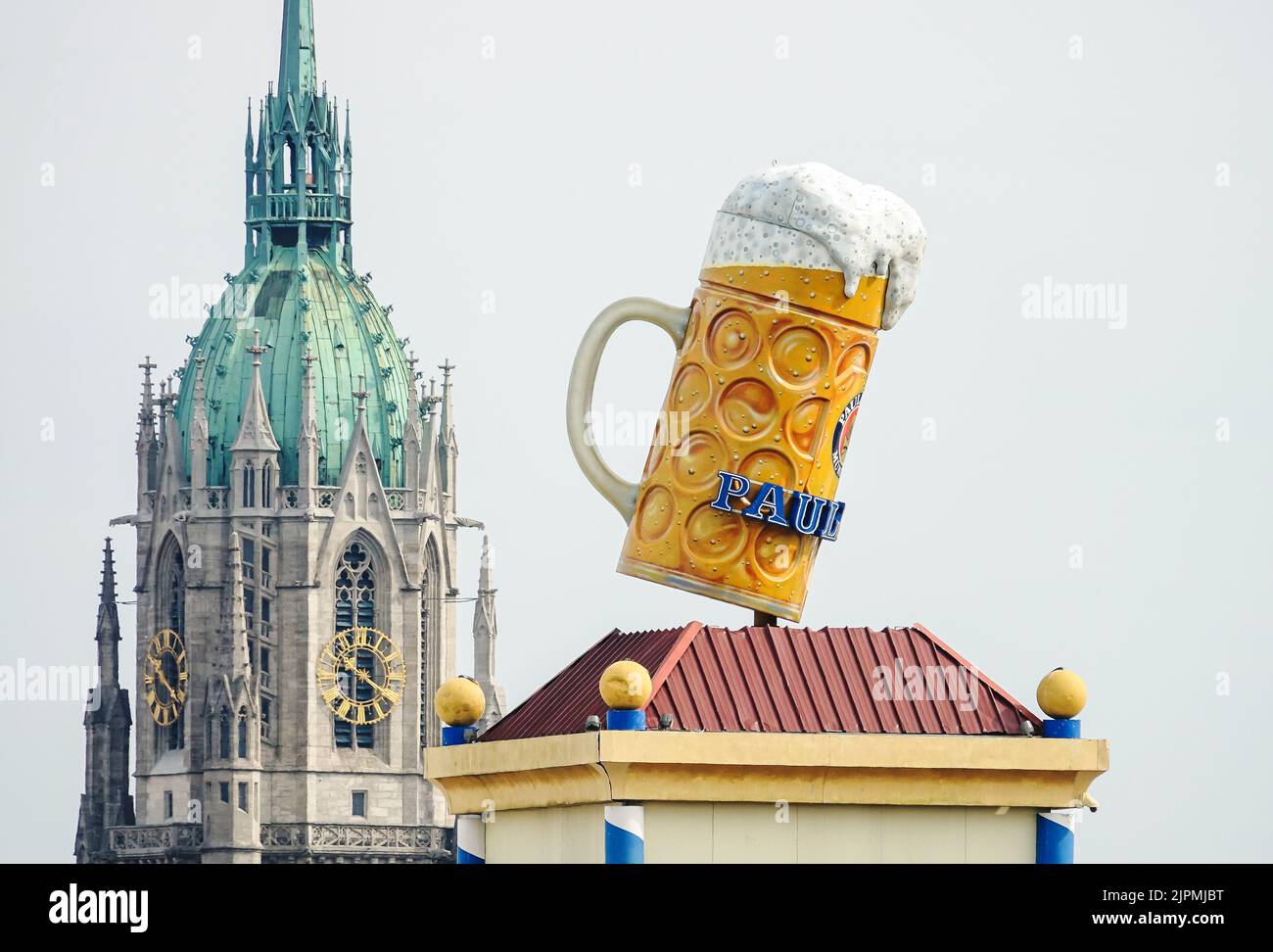 Oktoberfest de Múnich, una gran taza de cerveza en Theresienwiese con el telón de fondo de la iglesia gótica de San Pablo. Munich, ALEMANIA - Agosto de 2022 Foto de stock