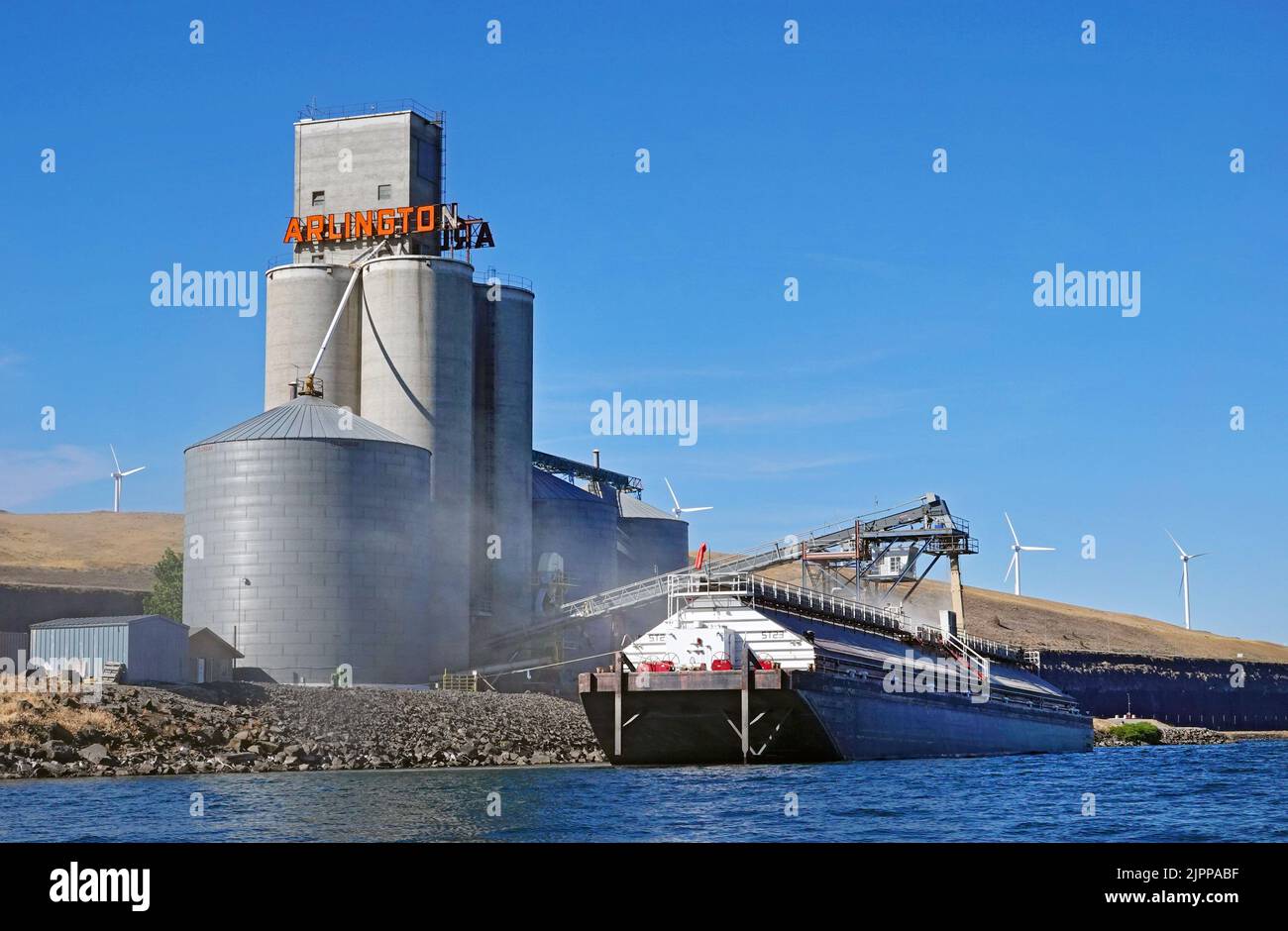 Una barcaza en el río Columbia, en el pequeño puerto de Arlington, Oregón, lleva una carga de trigo recién cortado de un enorme silo situado en la costa. Foto de stock