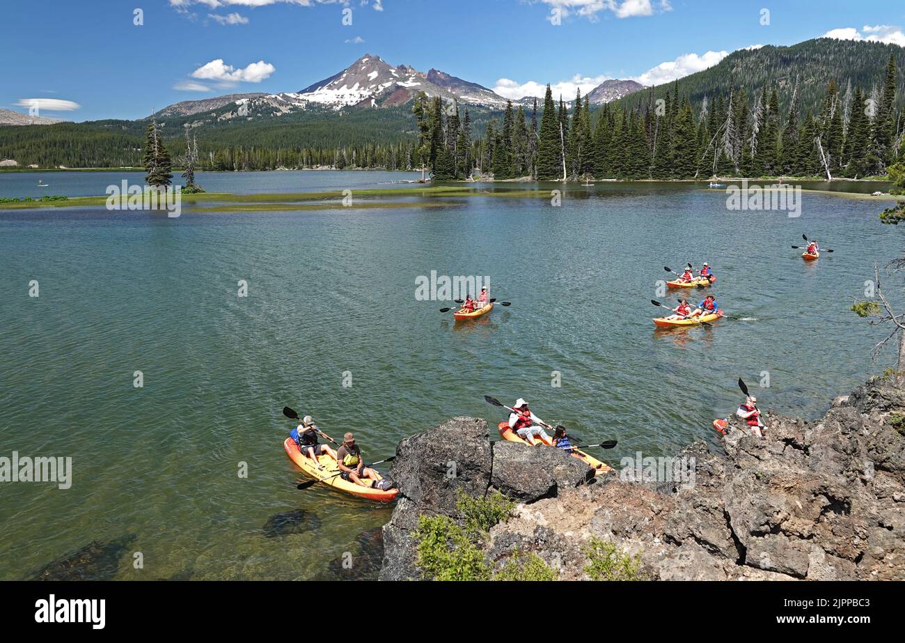 Los kayakistas disfrutan de un día de verano en Sparks Lake cerca de un pico nevado South Sisters Peak en las Oregon Cascades a principios de julio. Foto de stock
