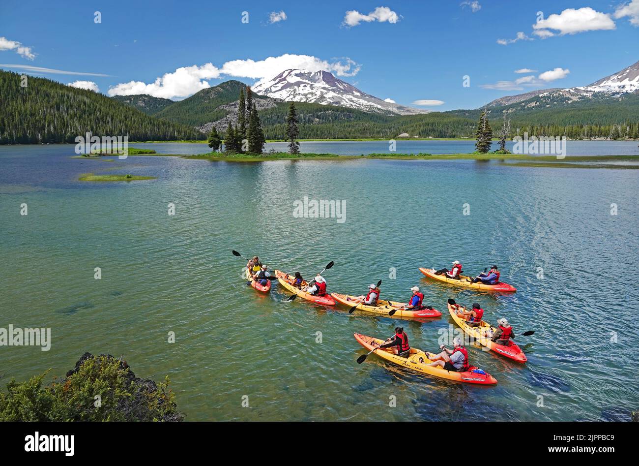 Los kayakistas disfrutan de un día de verano en Sparks Lake cerca de un pico nevado South Sisters Peak en las Oregon Cascades a principios de julio. Foto de stock