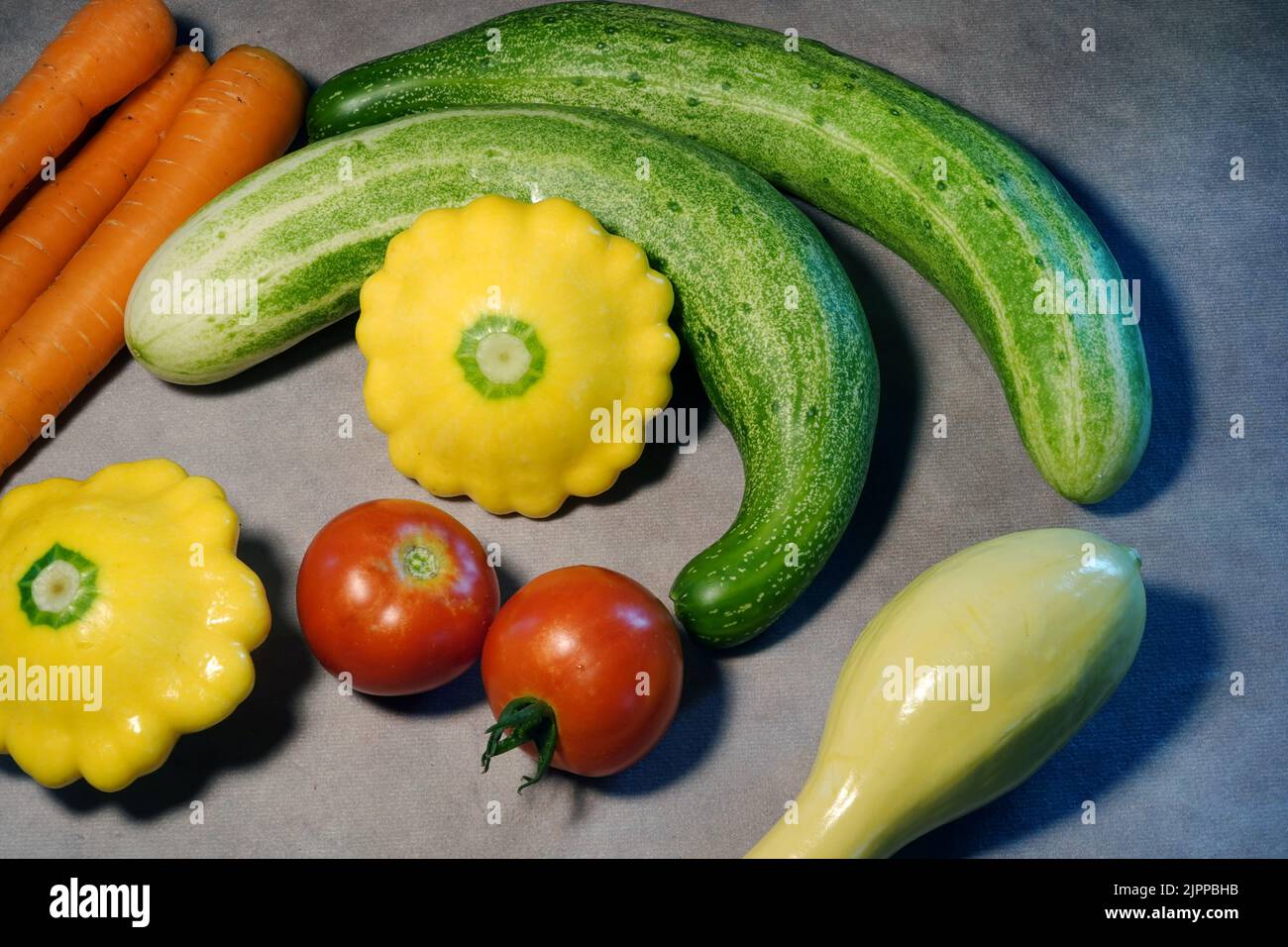 Una variedad de verduras frescas, justo fuera de un jardín casero, incluyendo pepinos, zanahorias, y calabaza. Foto de stock